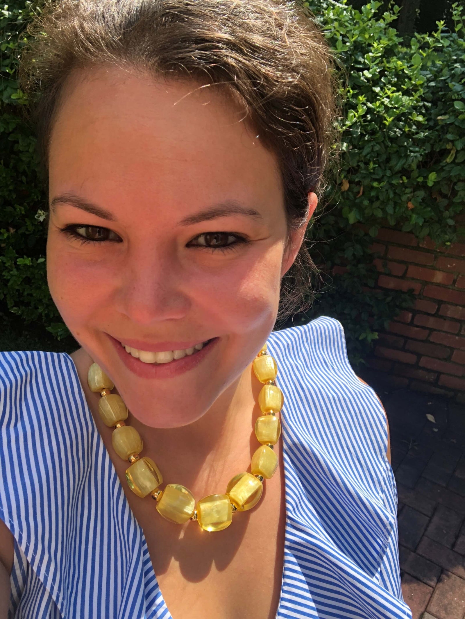 Woman wearing a yellow necklace with a foliage background