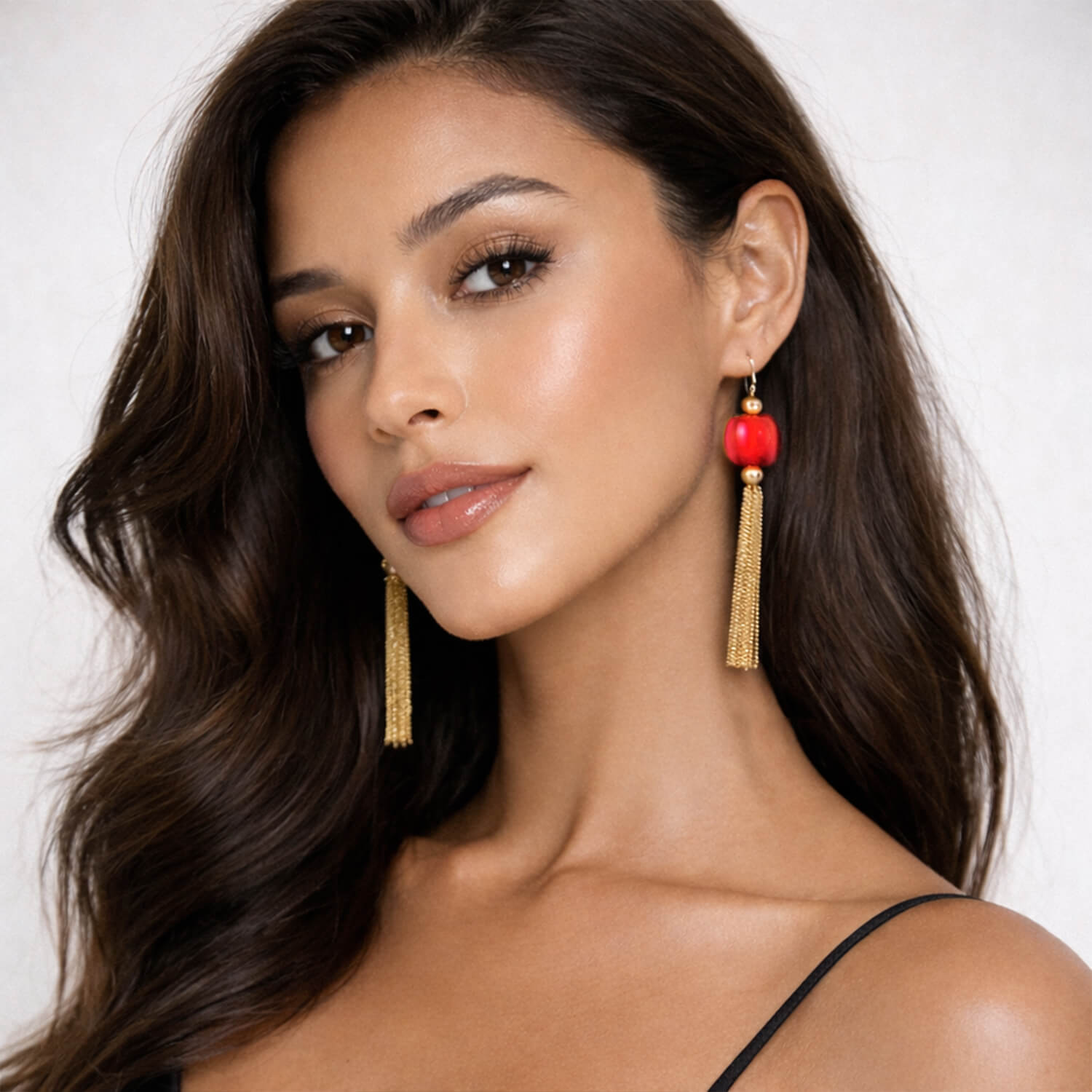 Woman wearing red and gold earrings against a white background