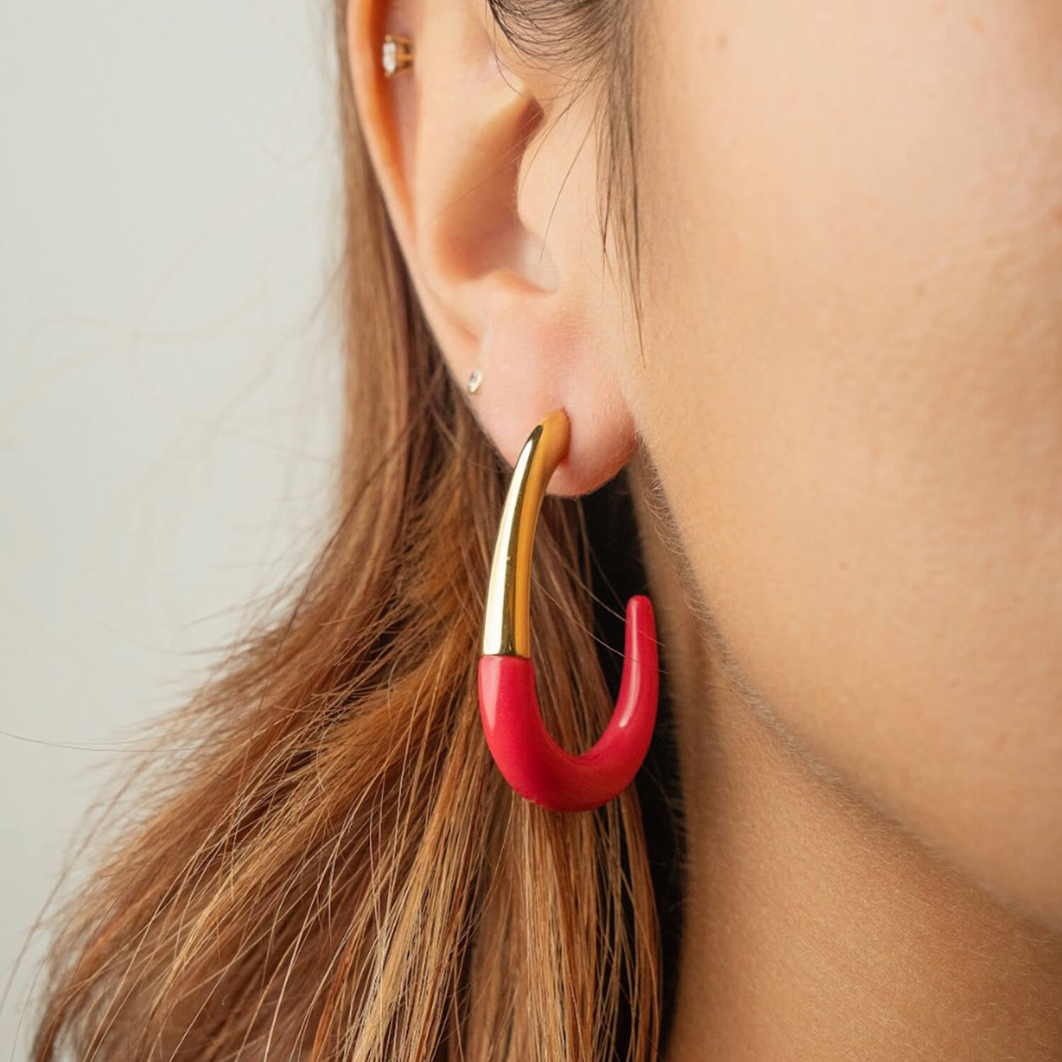 Close-up of a person wearing a pink and gold hoop earring.