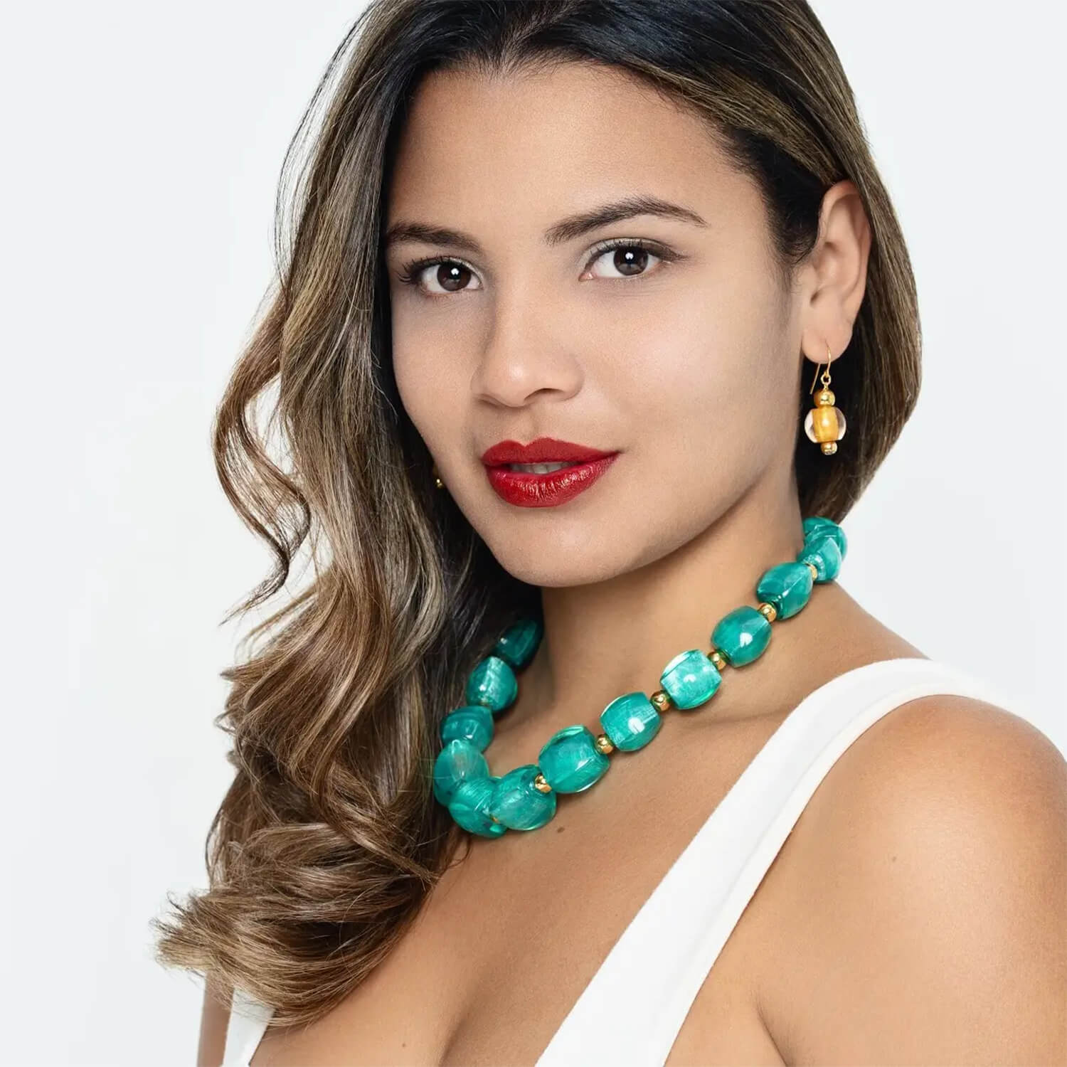 Woman wearing a TEAL necklace and earrings on a white background