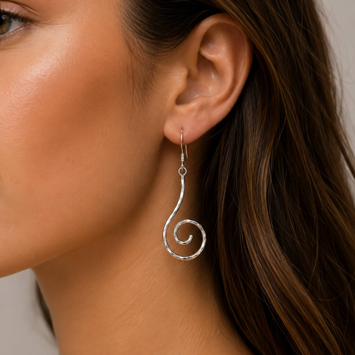 Close-up of a woman wearing a silver spiral earring.