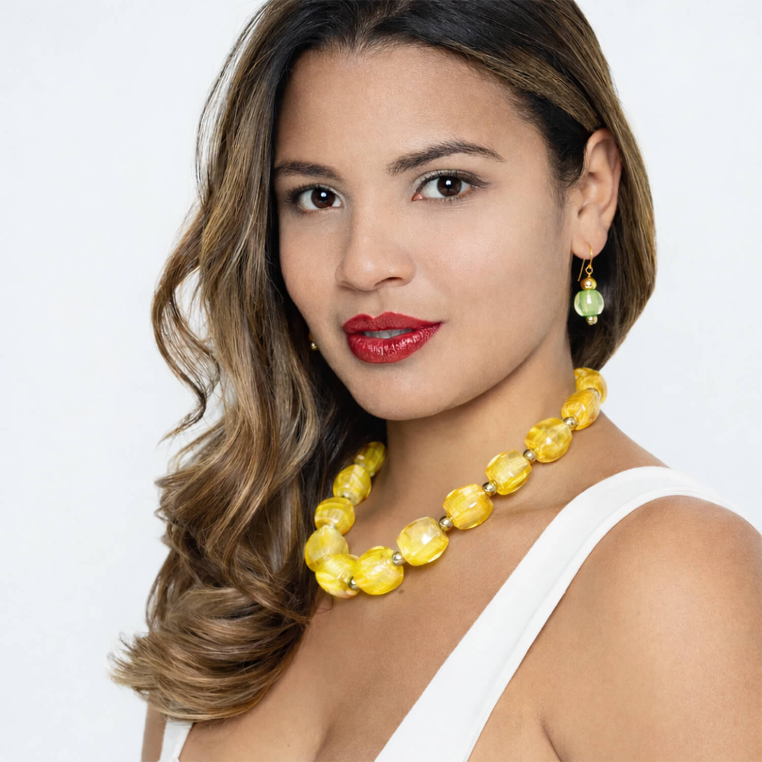 Woman wearing a yellow necklace and earrings on a white background