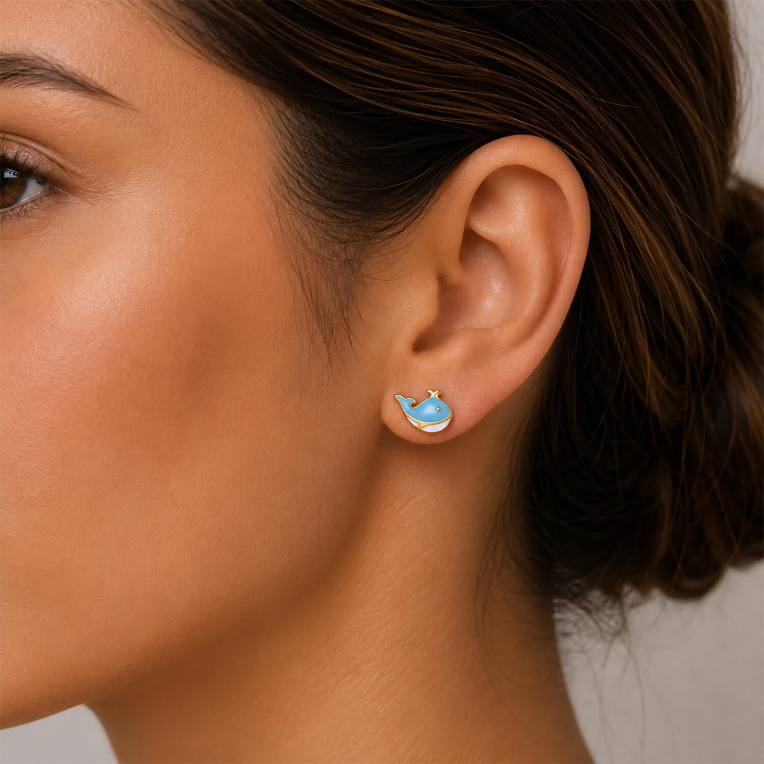 Close-up of a woman's ear wearing a whale-shaped earring.