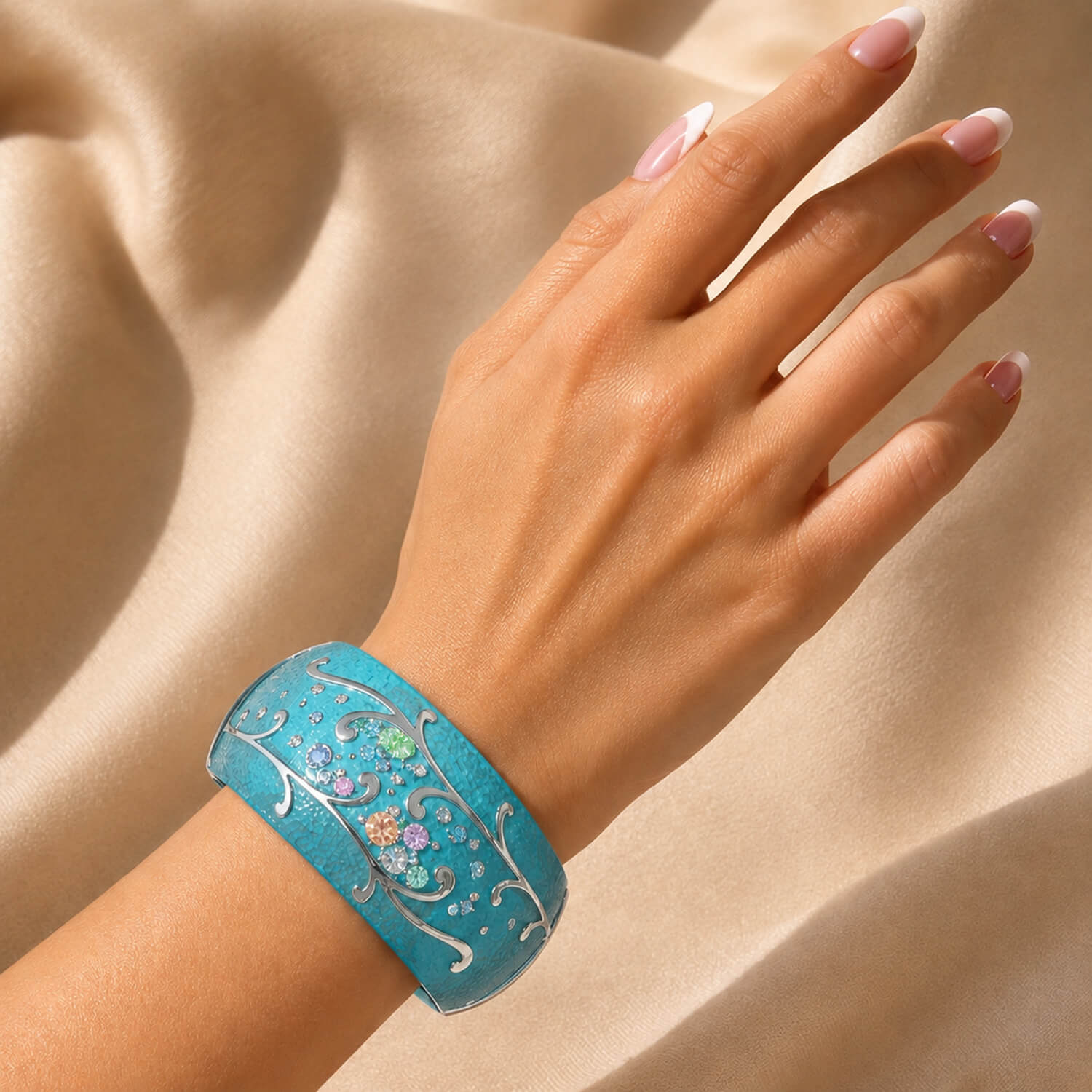 Hand wearing a blue bracelet with floral designs on a beige fabric background