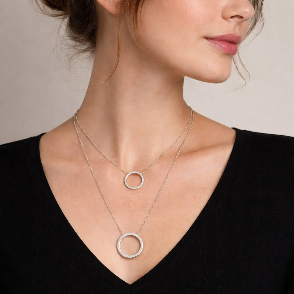 Woman wearing a silver necklace with circular pendants against a neutral background