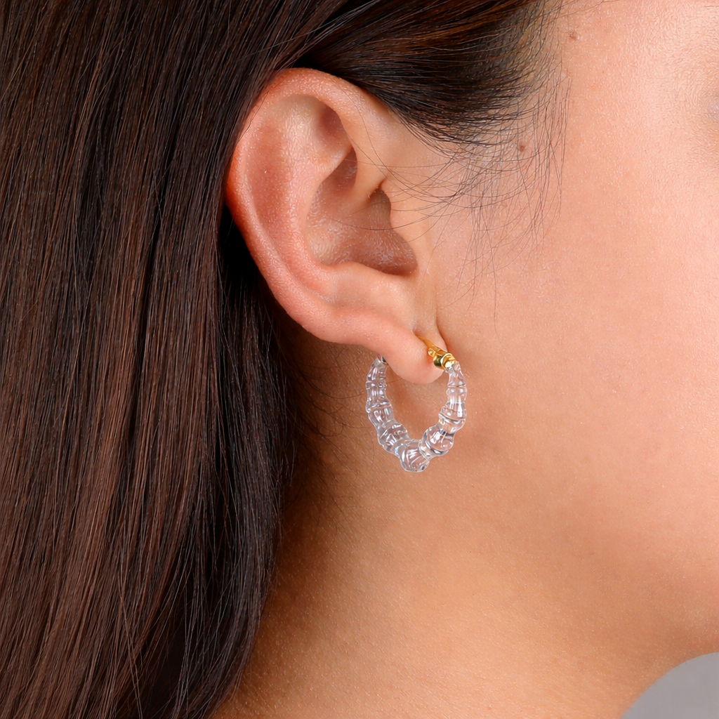 Close-up of an ear wearing a clear hoop earring with gold accents.