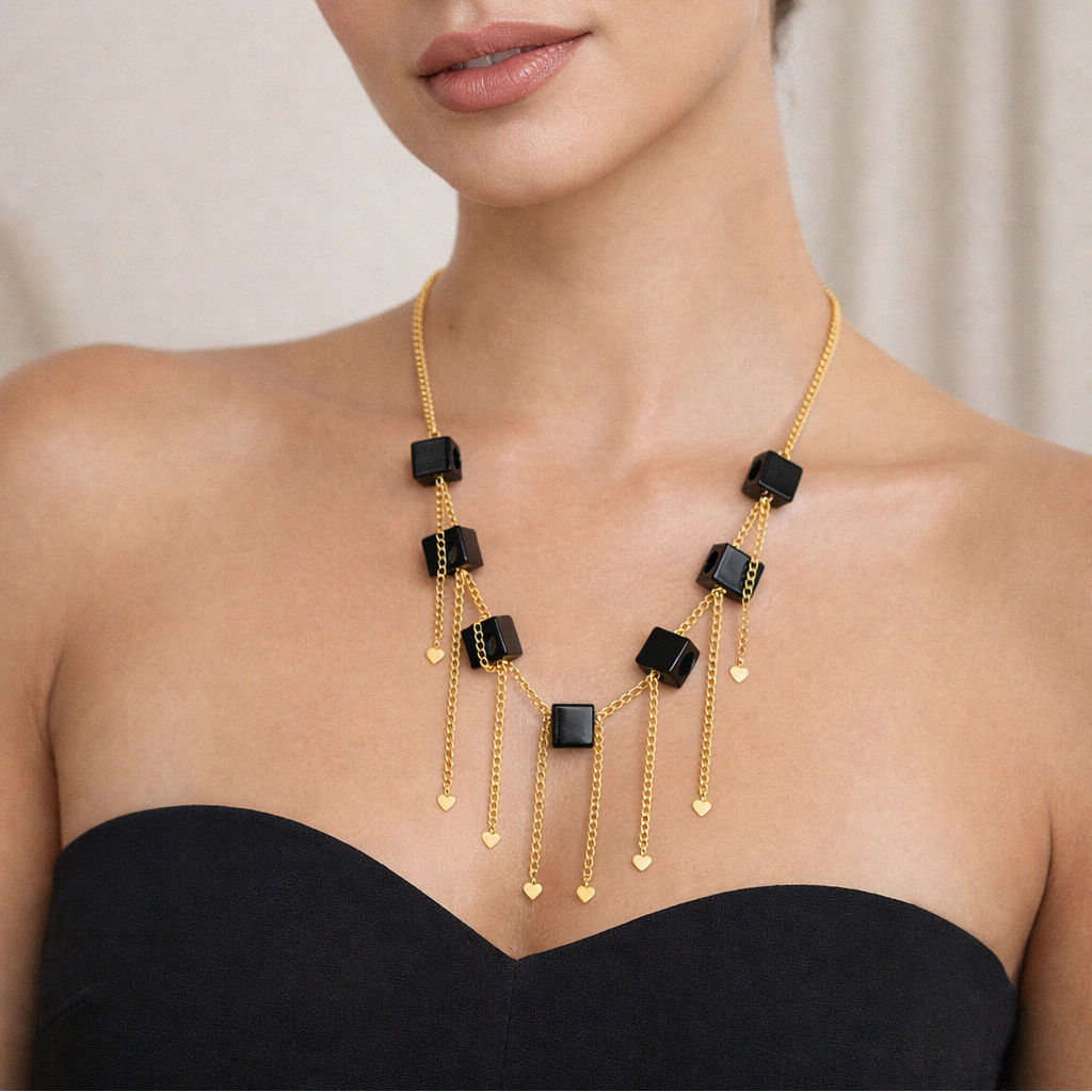Woman wearing a gold and black necklace against a neutral background