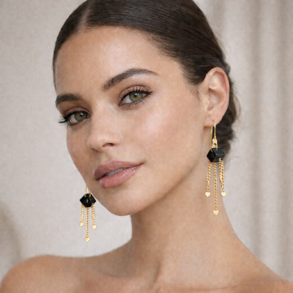 Gold chain earrings with black geometric pendants on a white background