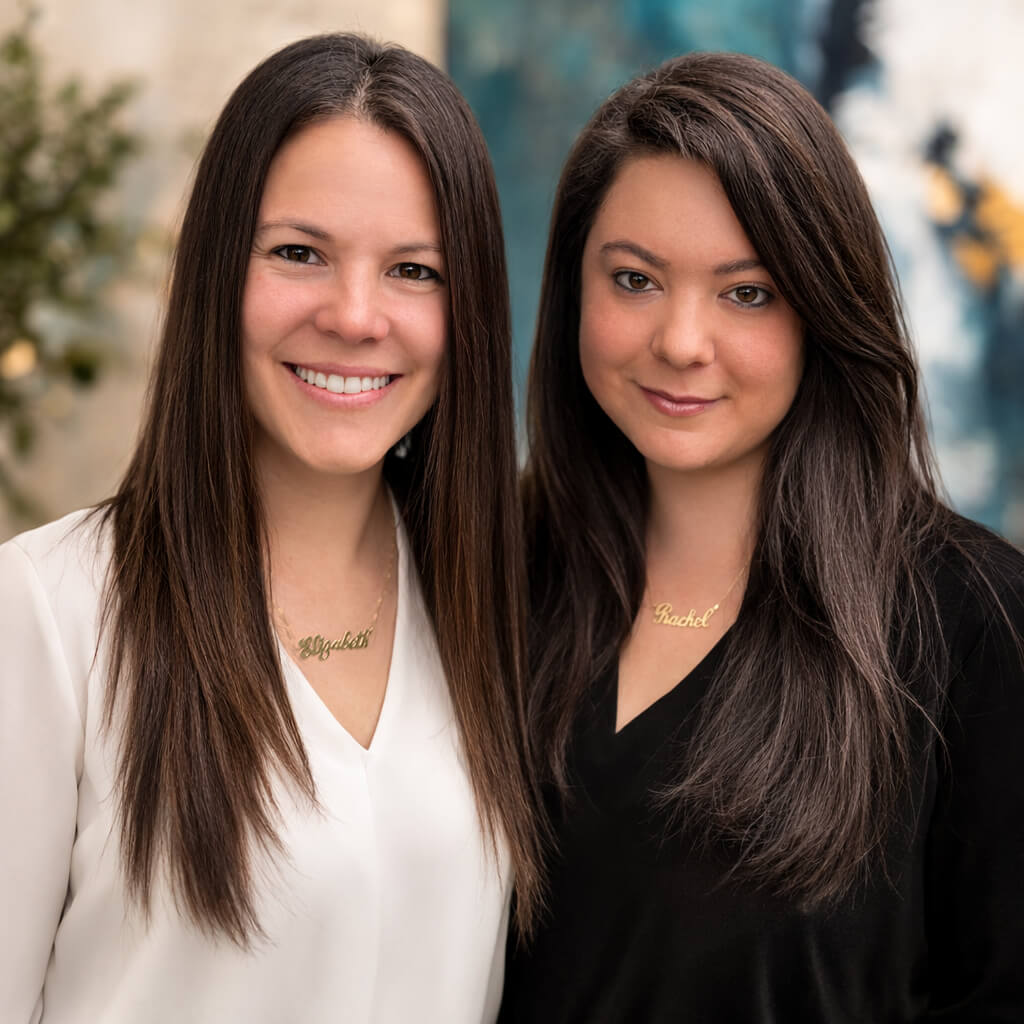 Two women standing side by side with a blurred background