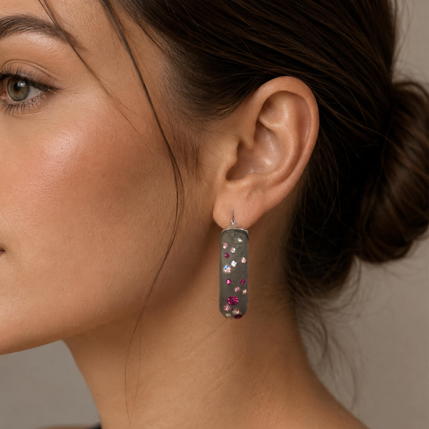 Close-up of a woman wearing a decorative earring with a neutral background
