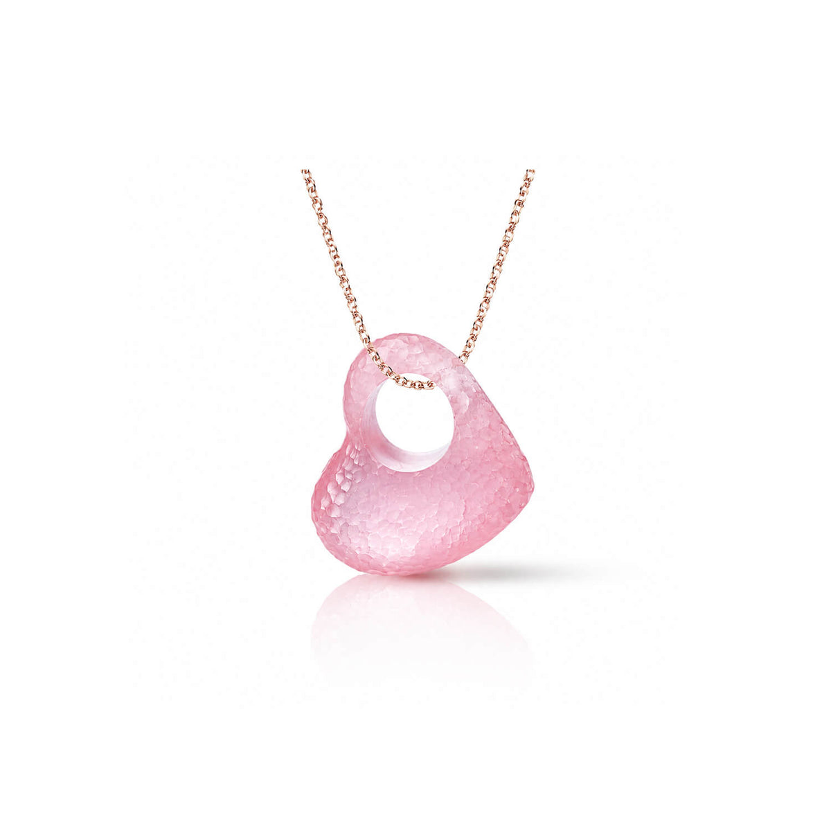 A pink textured pendant necklace with a heart-like organic shape and a central hole, suspended from a delicate rose gold chain on a white background.