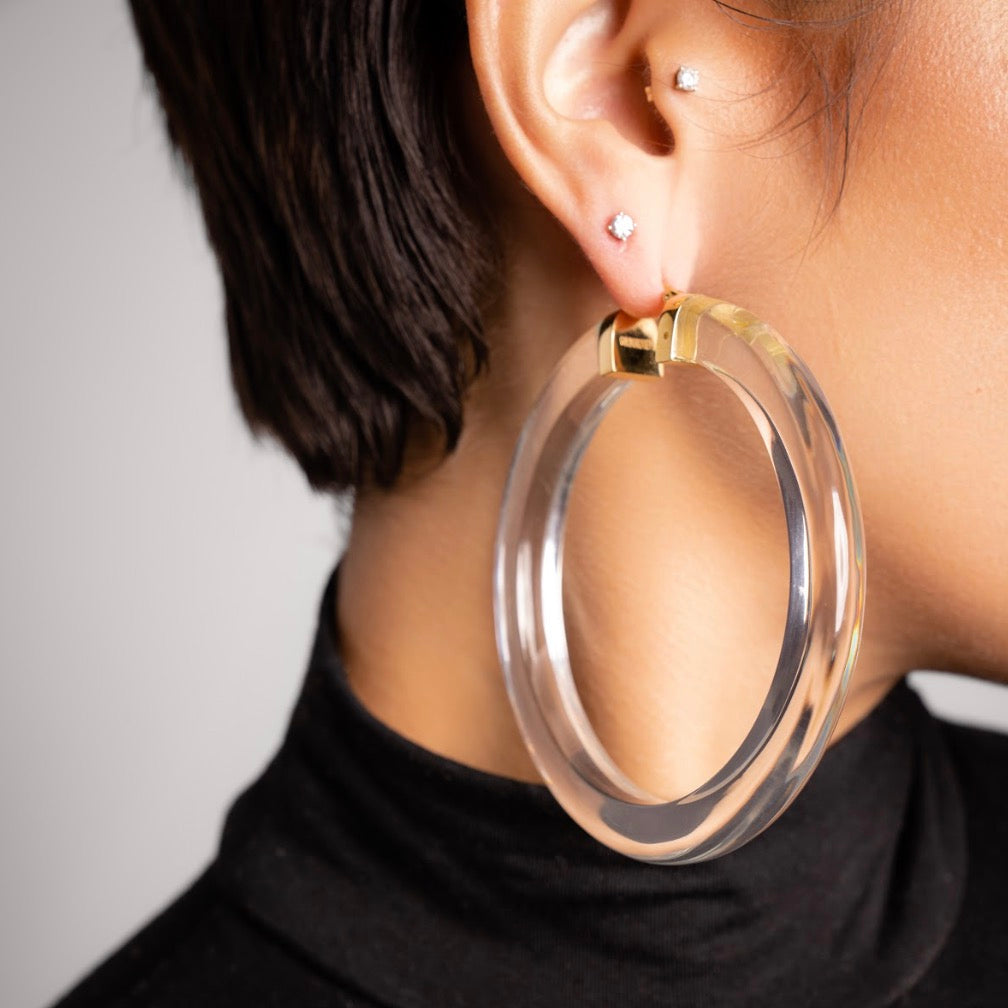 Clear hoop earring worn by a person with a neutral background