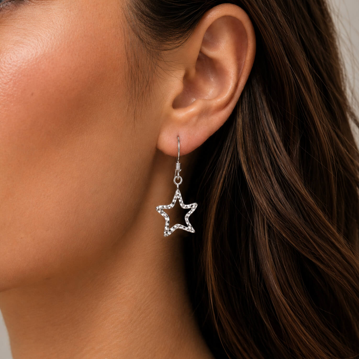Star-shaped earring worn by a person with brown hair.