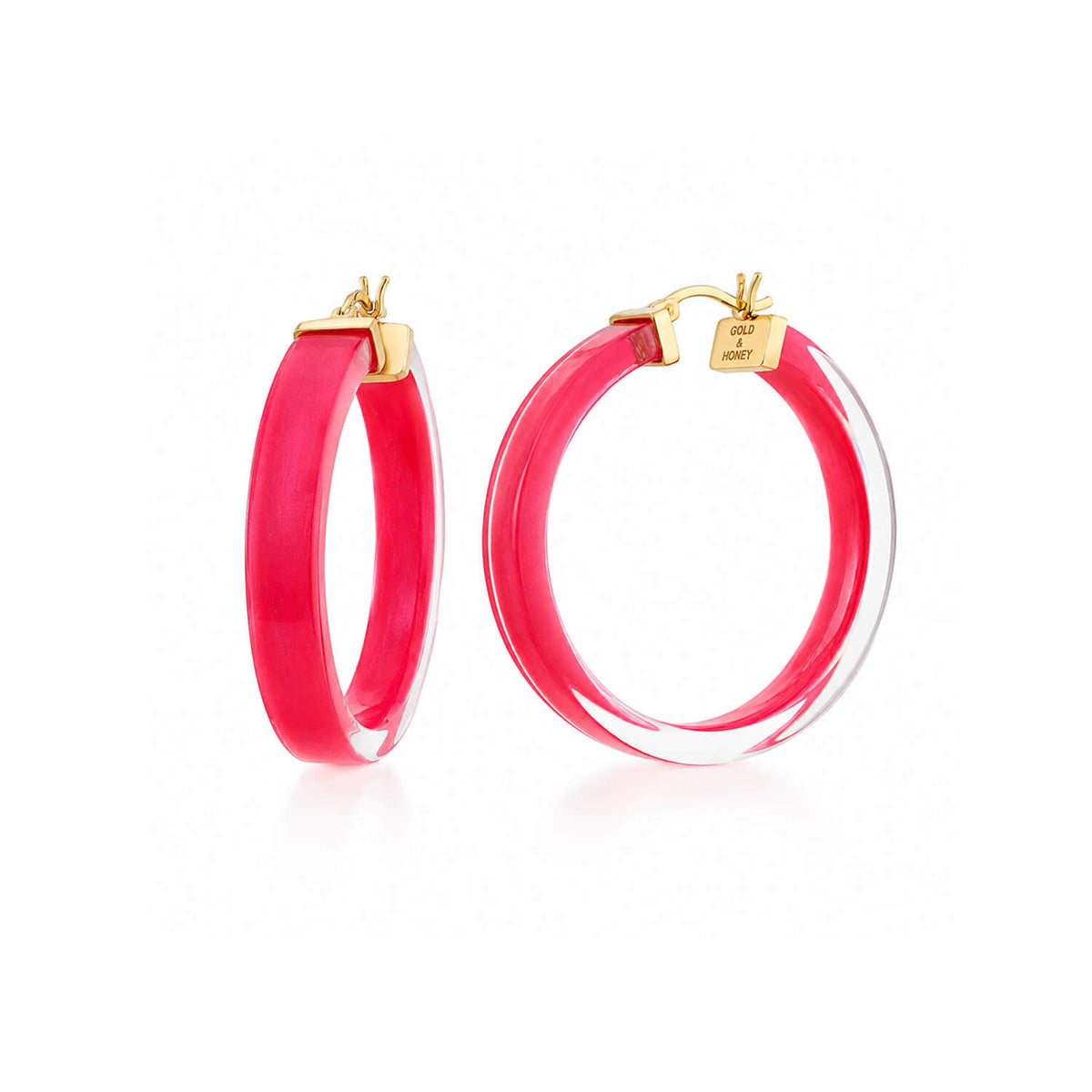 A pair of large hoop earrings with a vibrant pink inner band and a clear outer ring, secured with gold-tone posts and backings, shown on a white background.