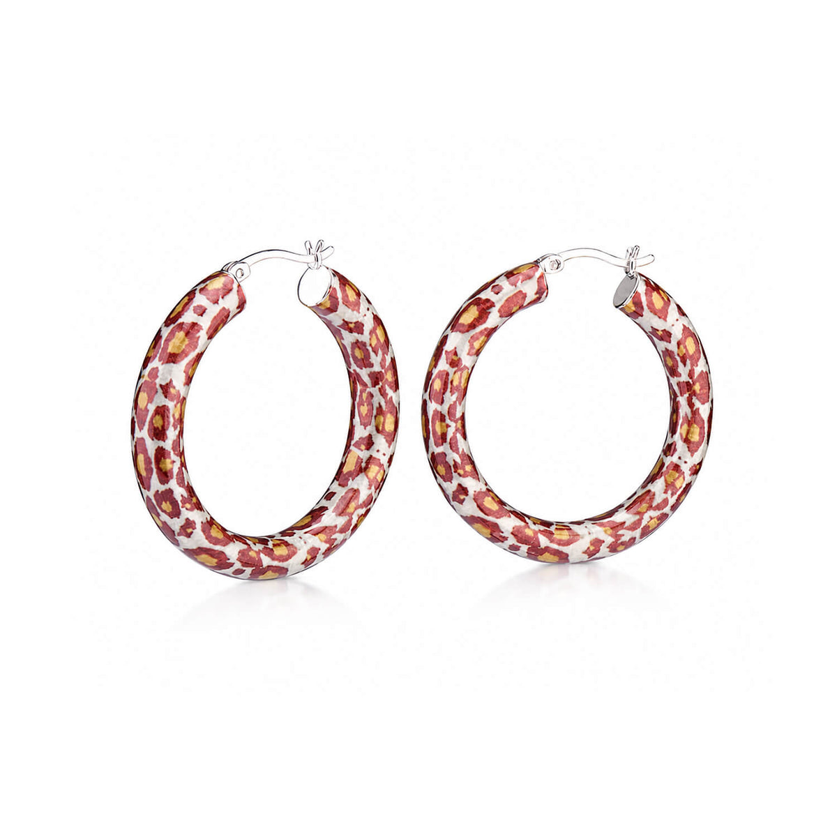 A pair of silver hoop earrings with a red, orange, and yellow spotted leopard pattern on a white background, shown on a clean white studio background.