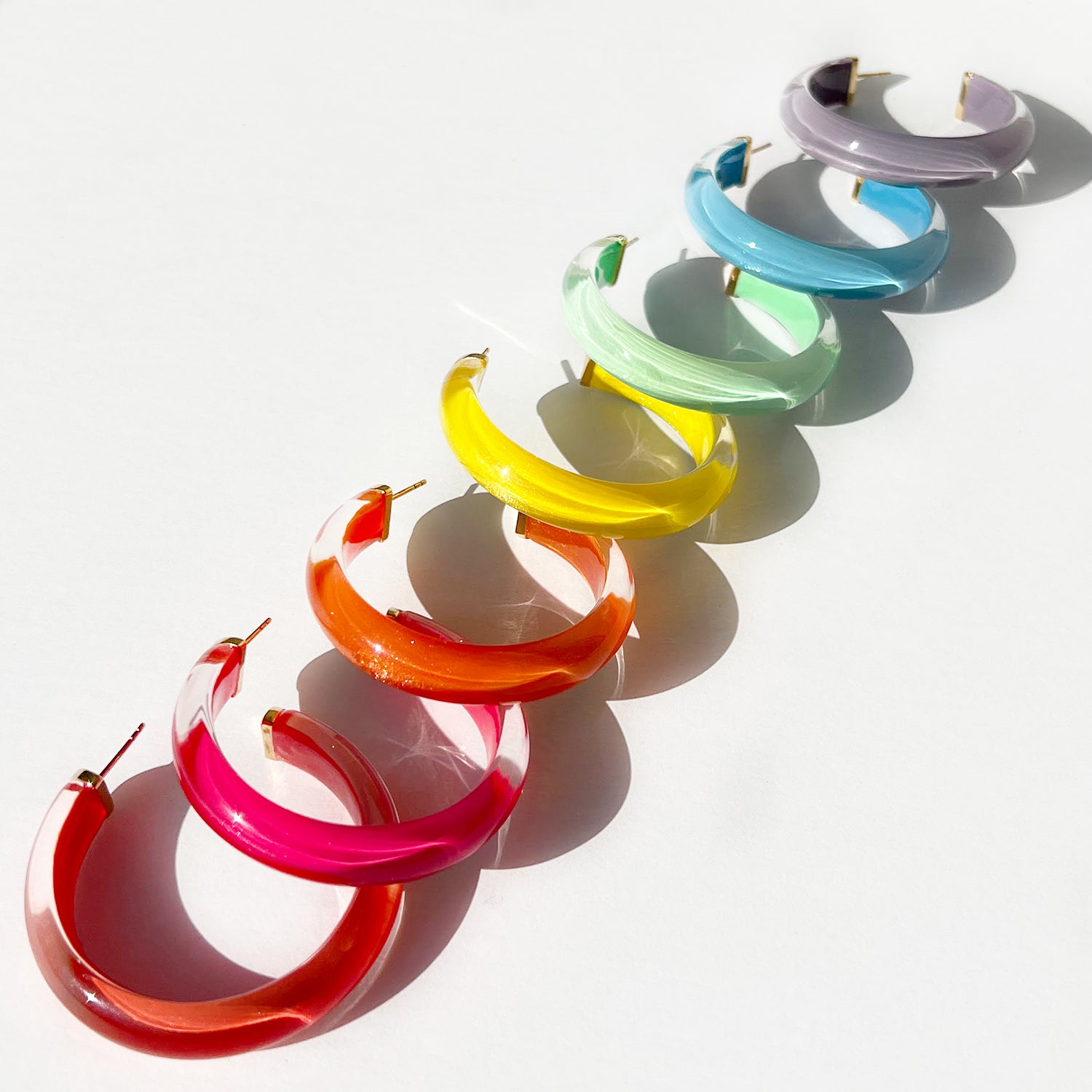 Colorful hoop earrings arranged in a row on a white background