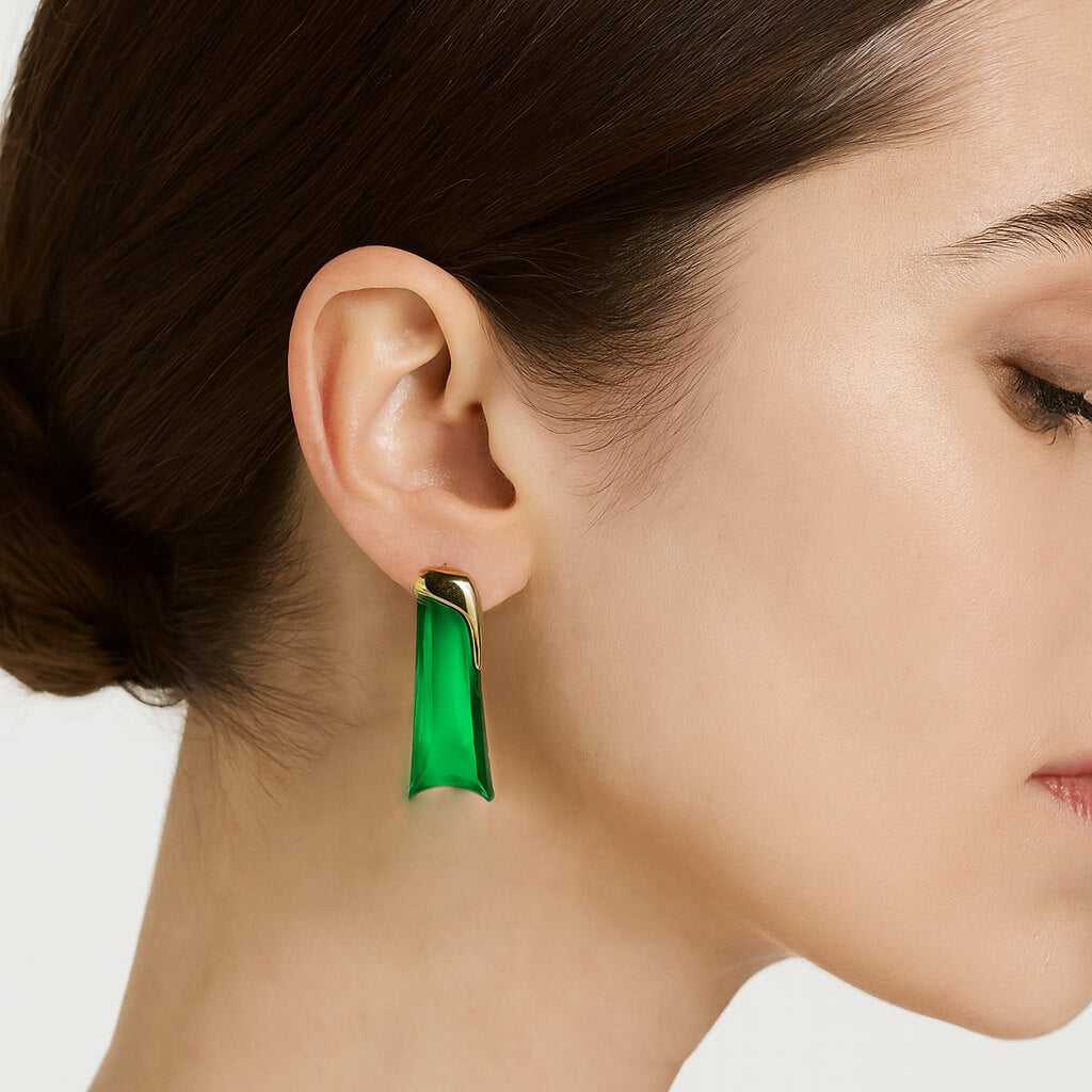 Close-up of a woman wearing a green earring with a neutral background