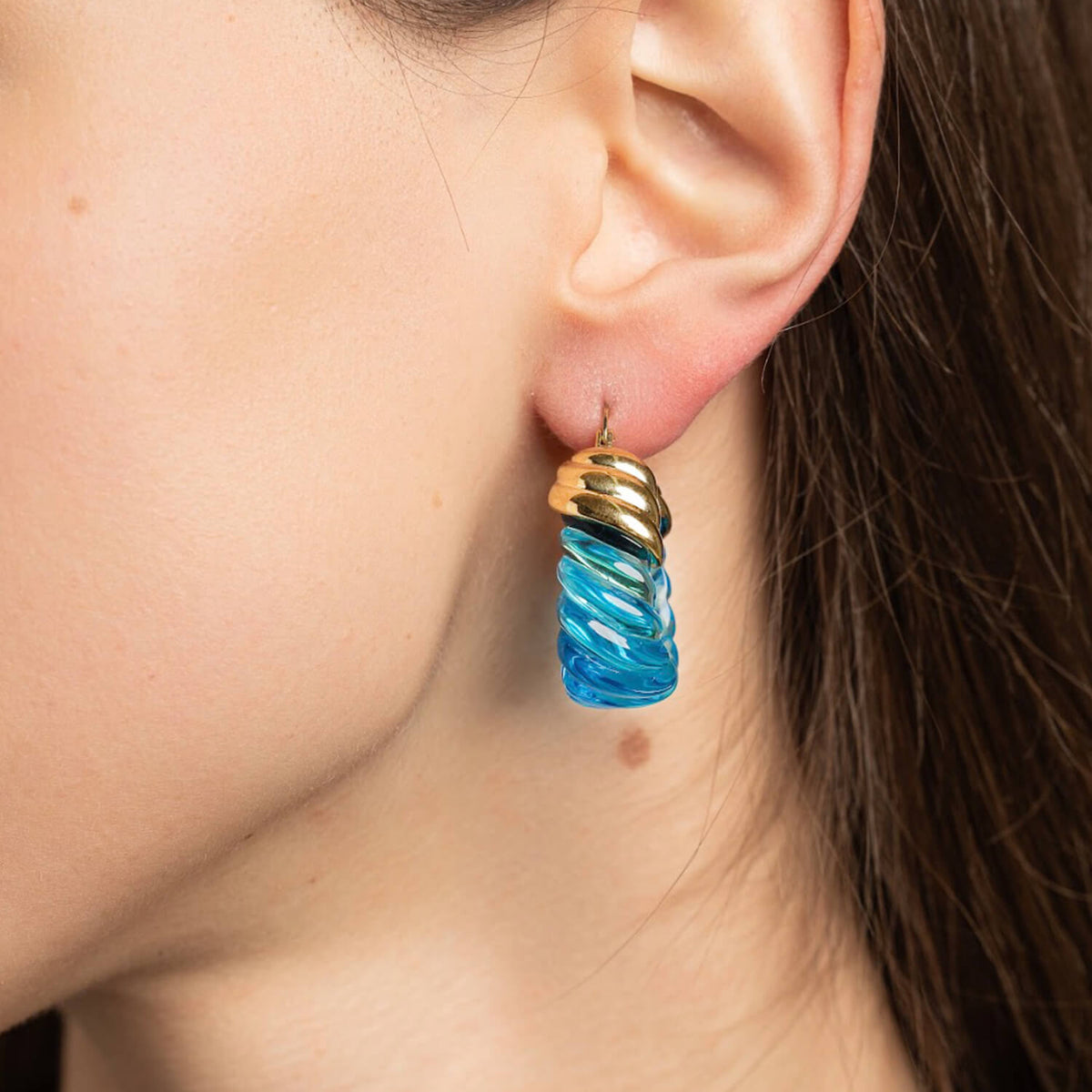 Close-up of a person wearing a blue and gold earring.