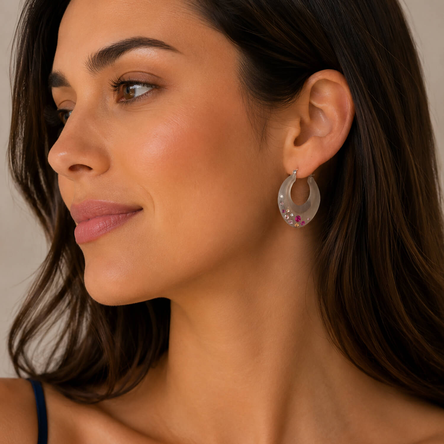 Close-up of a woman wearing hoop earrings with a neutral background