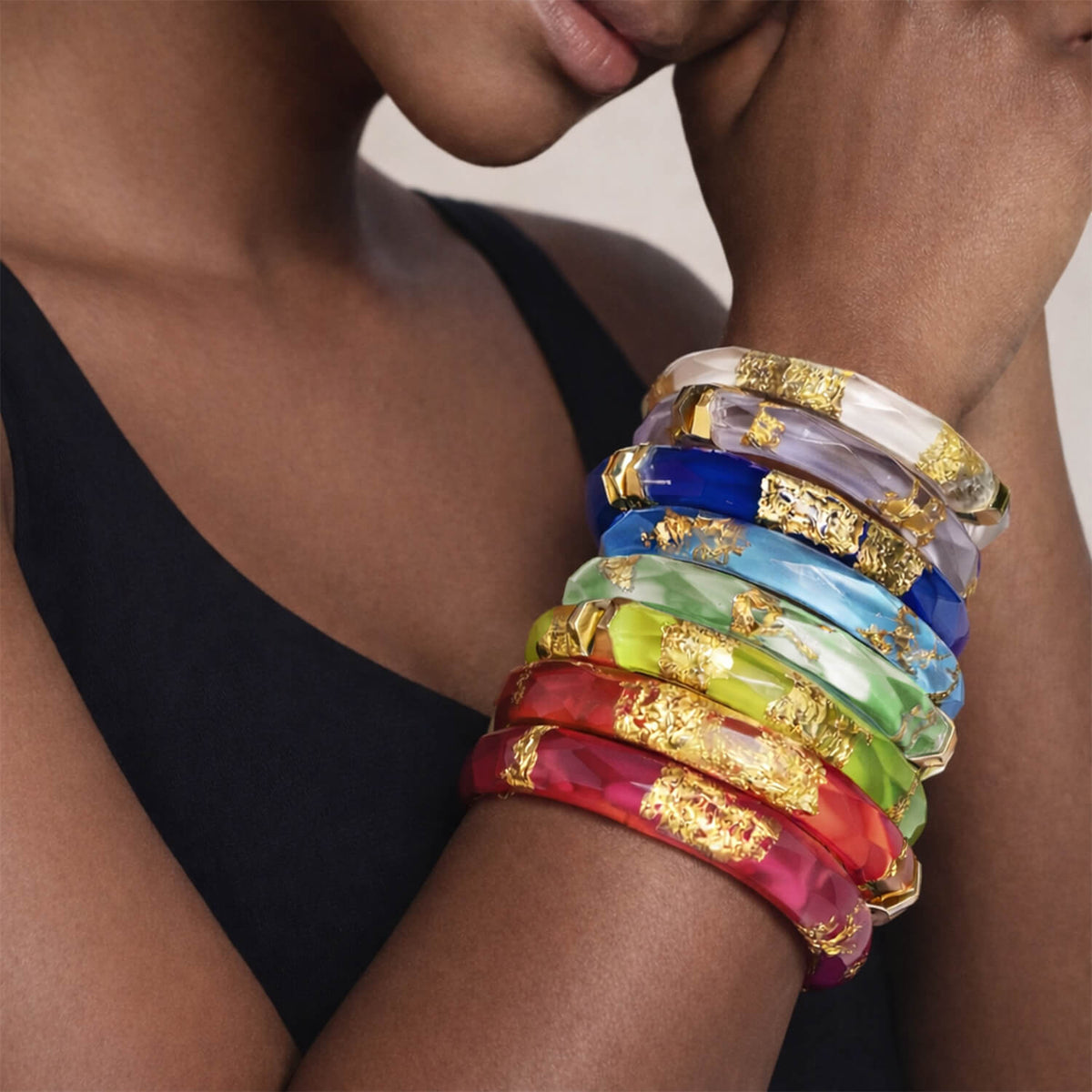 Stack of colorful bracelets with gold accents on a person's wrist.