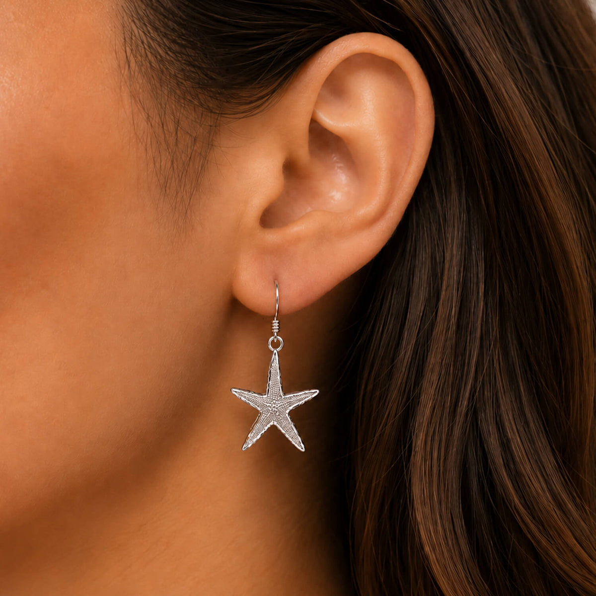 Starfish earring worn by a person with brown hair.