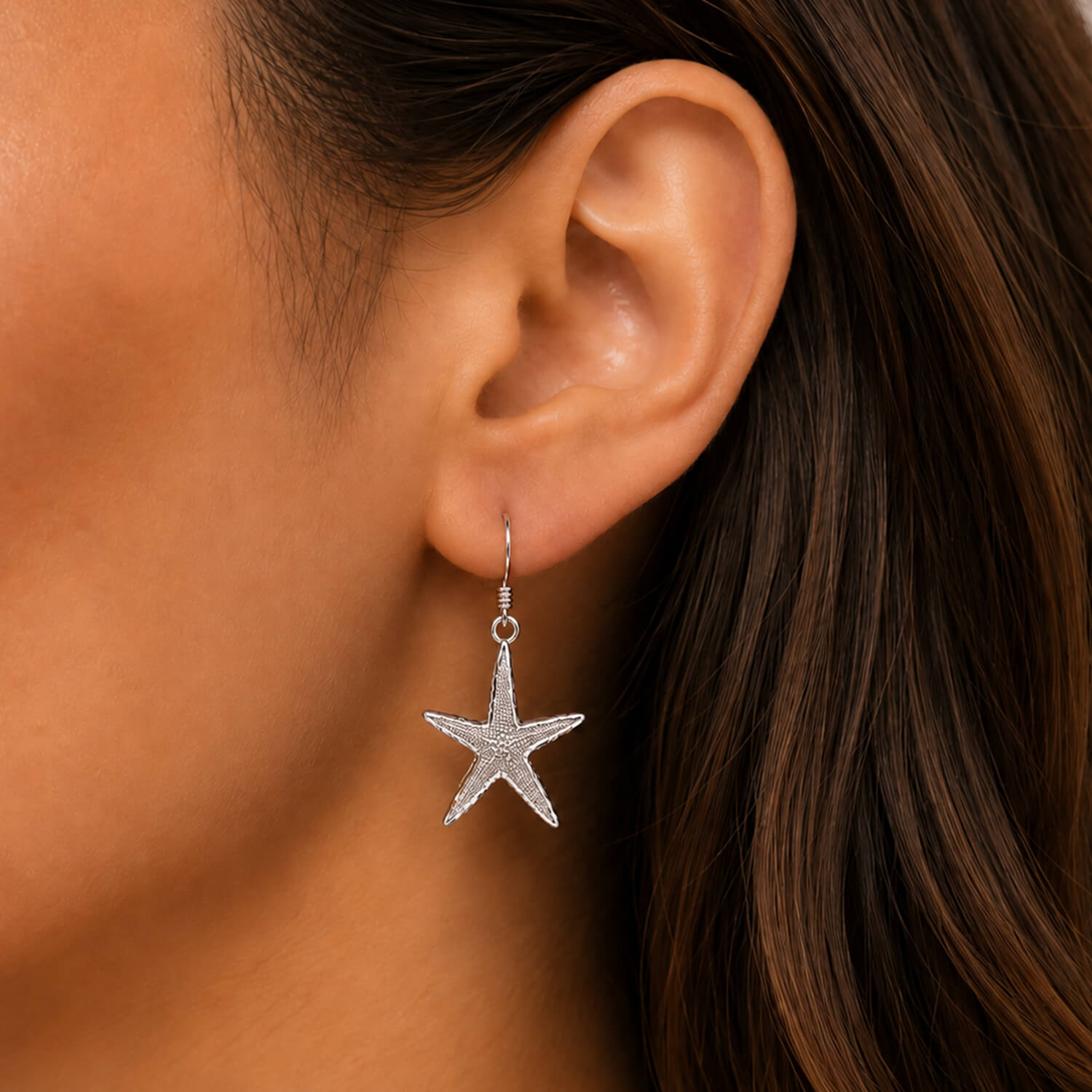 Starfish earring worn by a person with brown hair.